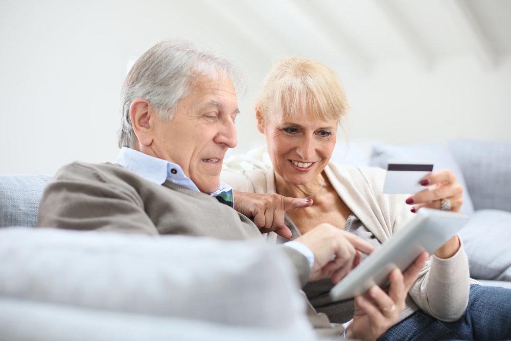 Couple de retraités souriants qui regarde leur tablette